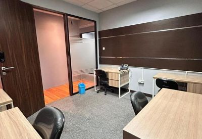 Modern office room with wooden desks and grey carpeting.