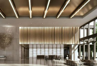 Spacious reception lobby with warm linear ceiling lights and a textured feature wall.