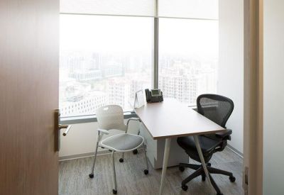 Private window office with a wooden desk and views of the city skyline.