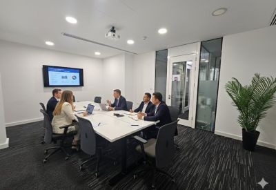 Professional meeting room with a large white table and wall-mounted monitor.