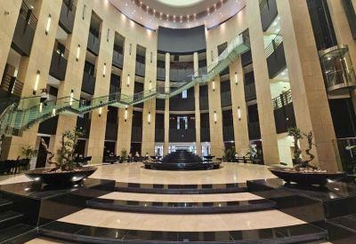 Grand multi-story atrium reception with a curved staircase and central water feature.