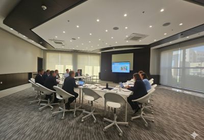Meeting room with professionals seated around a large white table for a presentation.