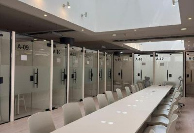 Spacious coworking area with a long shared table under a large skylight.