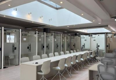 Modern open-plan workspace featuring rows of desks and glass-partitioned offices.
