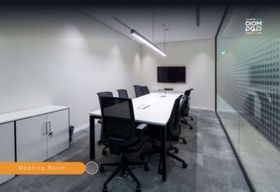 Professional meeting room with a long white table, black mesh chairs, and a wall-mounted TV.