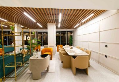 Bright shared workspace area with an orange armchair and long dining-style marble table.
