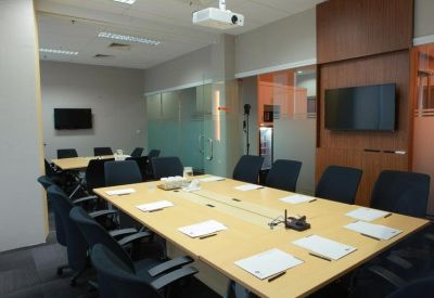 Large conference room with multiple workstations, wall-mounted monitors, and a ceiling projector.
