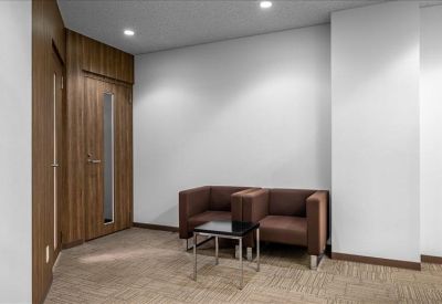 Modern lobby area with wood paneling and two brown leather armchairs.