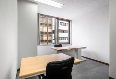 Two-person private office with light wood desks and views of the neighboring buildings.