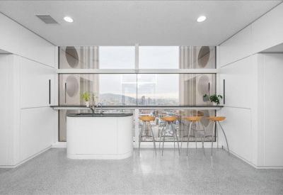 Communal break area with a white curved counter and stools overlooking a window.