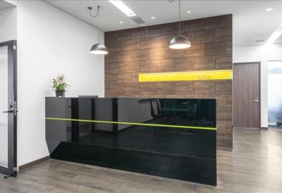 Modern reception desk with a black glass finish and wood-paneled feature wall.