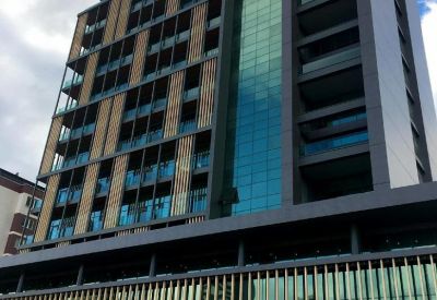 Modern exterior of the high-rise Konak Mahallesi, Lefkoşe Cd building with glass and wood paneling.