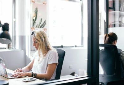 Professional workspace with a woman working on a laptop near a window.