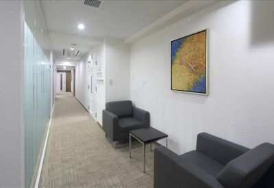 Modern hallway lounge area with grey armchairs and abstract wall art.