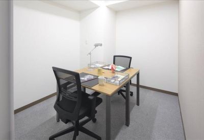 Bright private office featuring a wooden desk and two ergonomic chairs.