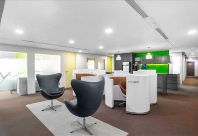 Bright communal lounge and breakout area featuring modern black egg chairs and a green accent wall.