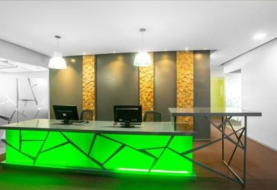 Professional reception area with a vibrant green illuminated front desk and textured wall panels.