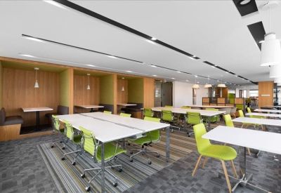 Spacious coworking area with long white tables and vibrant green chairs.