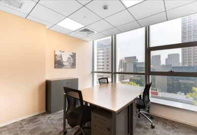 Private office suite with a wooden desk and city skyline views through large windows.