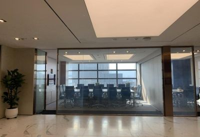 Spacious boardroom behind a glass partition with a large table and panoramic window views.