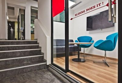 Small meeting room with blue chairs and a wall-mounted screen.