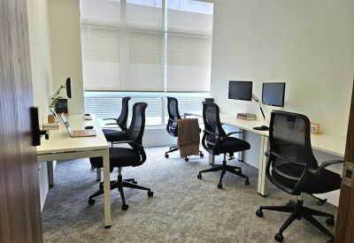 Four-person internal office suite featuring white desks, black mesh chairs, and large frosted windows.