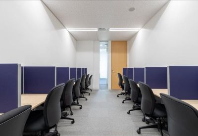 Coworking space featuring rows of individual workstations separated by blue privacy screens.