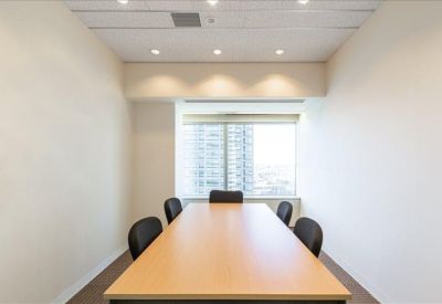 Small private meeting room with a light wood table and six black chairs.