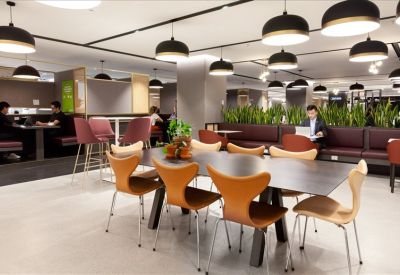Modern coworking lounge with tan designer chairs and contemporary black pendant lighting.
