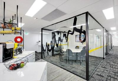 Communal kitchen area with a fruit bowl and views into a glass-walled meeting room.