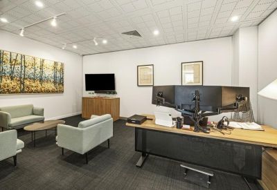 Private office suite with a dual-monitor workstation and lounge area.