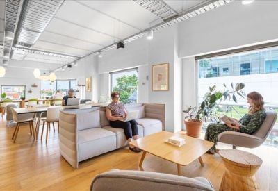 Light-filled breakout lounge featuring comfortable sofas, a coffee table, and indoor plants.