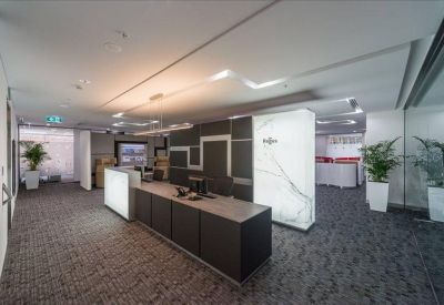 Modern reception area with a dark wood desk and illuminated white stone pillars.
