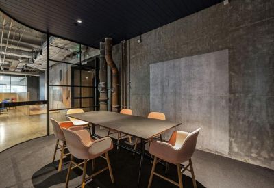 Private meeting room with a dark table, pink velvet chairs, and concrete feature wall.