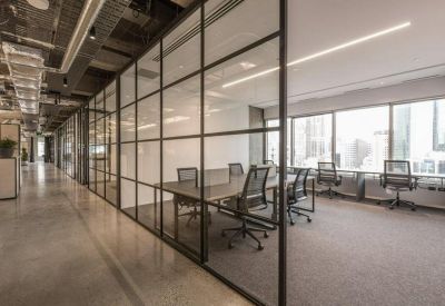 Glass-walled conference room adjacent to a brightly lit office corridor.