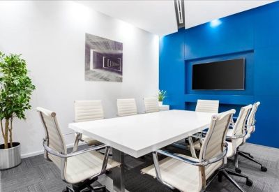 Professional meeting room with a large white table, blue accent wall, and integrated wall-mounted TV.