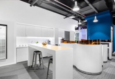 Contemporary breakout area with a high white breakfast bar, stools, and exposed ceiling pipes.