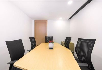 Professional meeting room with a light wood table and black mesh chairs.