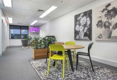 Communal dining area with a round table, colorful chairs, and floral artwork.