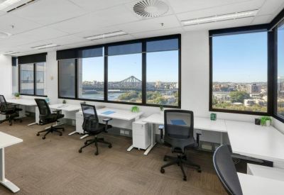 Bright open-plan office desks featuring expansive river views through large windows.