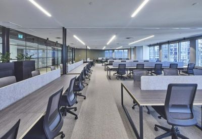 Large open-plan office floor with rows of grey workstations and ergonomic chairs.