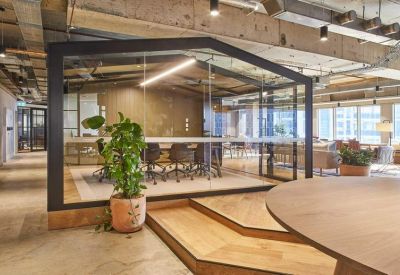 Modern glass-walled meeting pod with timber accents and an indoor plant.