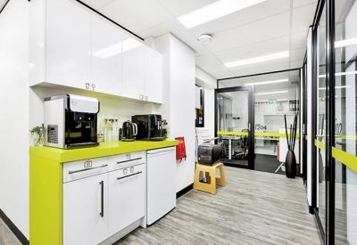 Communal kitchen area with lime green countertops and modern coffee machines.