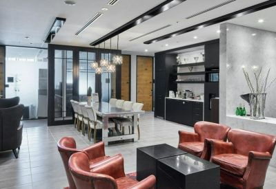 Lounge area featuring red leather armchairs and a communal dining table near a kitchenette.