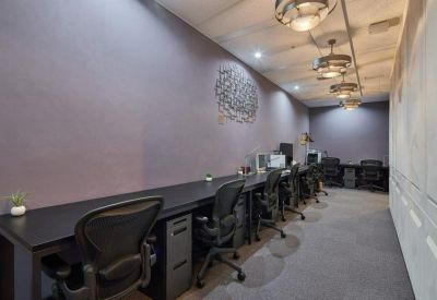 Co-working space with a long black desk, ergonomic chairs, and modern spherical pendant lighting.