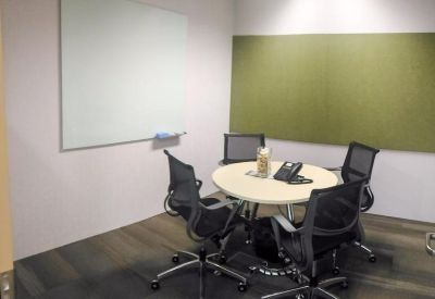 Small four-person meeting room with a round table and a green feature wall.