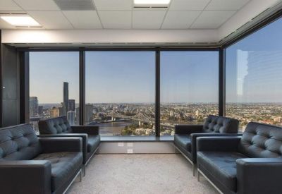Executive lounge with black leather armchairs and expansive panoramic city and river views.