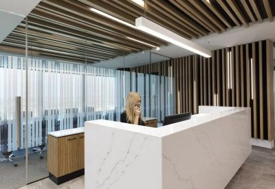 Modern reception desk with marble finish, wood slat ceiling, and vertical timber wall features.