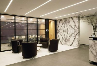 Modern reception area featuring a striking book-matched marble feature wall and black tub chairs.