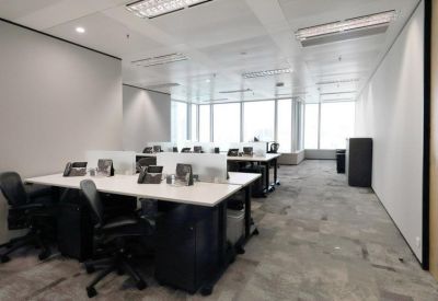 Open-plan office space with white desks, ergonomic black chairs, and bright window views.